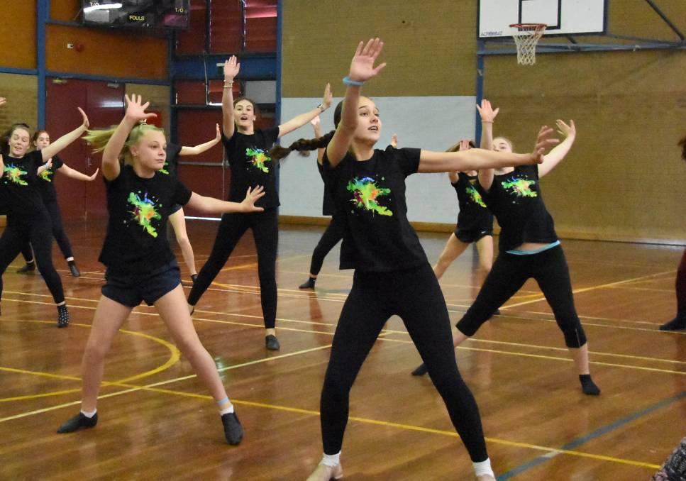 group of students rehearsing in a school hall in black tights and tshirts