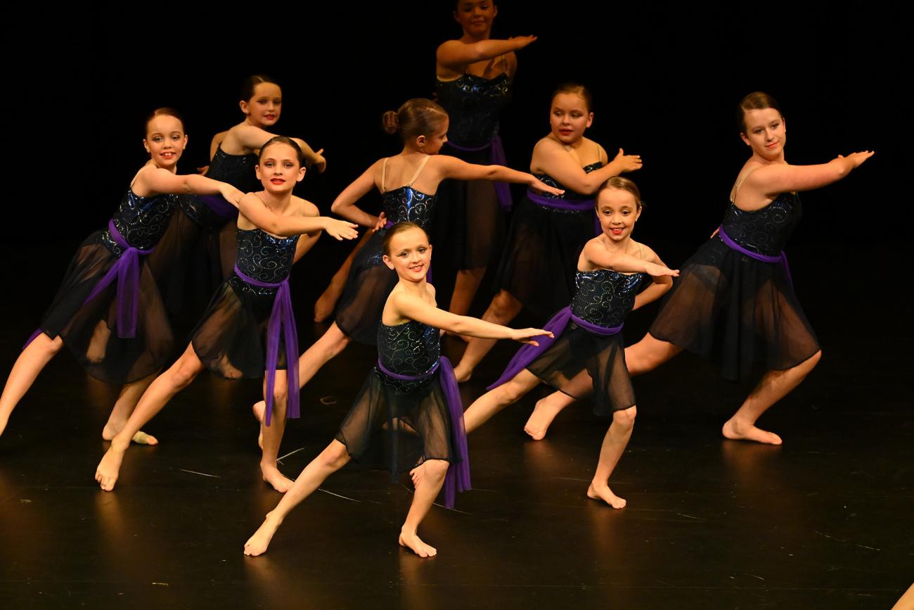 group of dancers on stage in purple dresses
