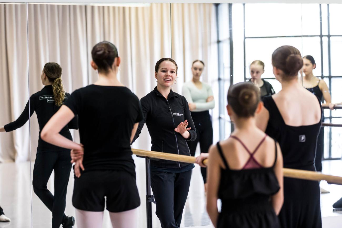 Ballet dancers at the barre in discussion with the teacher