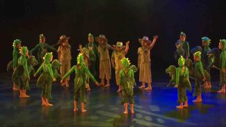 A scene from the work Dinosaurs (State Dance Festival 2019), students dressed as dinosaurs surround other students playing park rangers.